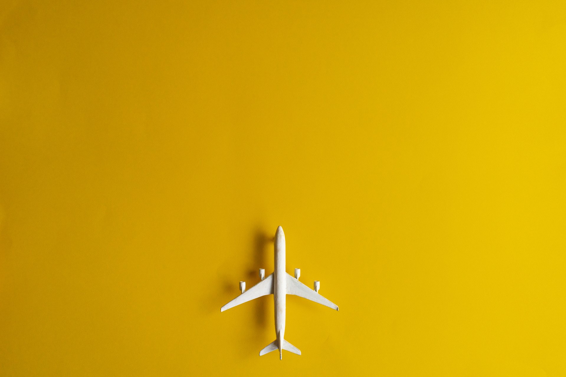 Miniature Toy Airplane on Yellow Background. Trip by Airplane.